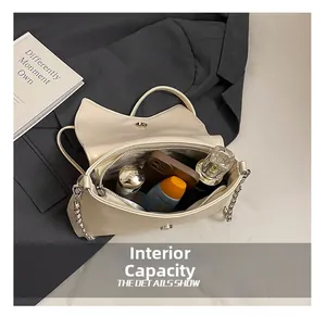 Detail view of beige cat-ear flap bag interior showing capacity for phone and cosmetics