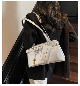 Close-up of metallic silver shoulder bag featuring a drawstring buckle and key pendant accessory