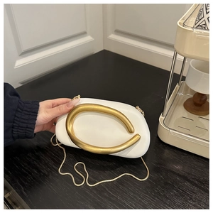 Detailed view of white pebble clutch bag with gold ring handle and metal chain strap