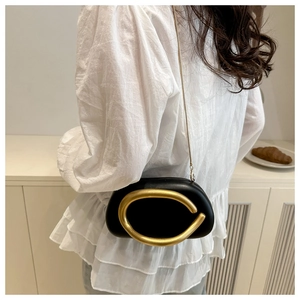 Detail of black PU crossbody bag with large gold oval metal ring on white blouse