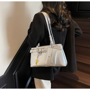 Detail of silver metallic tote bag with industrial buckles and yellow key charm
