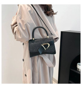 Detailed view of chic black sequin handbag with gold D-buckle and elegant top handle