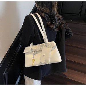 Detail view of cream shoulder bag with mini pouch and gold key charm on faux leather