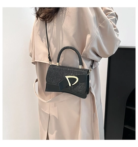 Detail of elegant black sequin handbag with gold D-buckle shown on model outfit