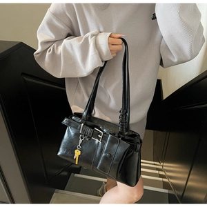 Detail of black glossy leather shoulder bag with metallic buckle and detachable mini pouch