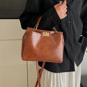 Brown crocodile pattern handbag with gold twist lock and adjustable shoulder strap