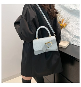 Detail of light blue glitter crossbody bag with golden triangular metal buckle closure