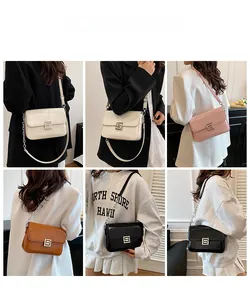 Close-up of minimalist leather flap bag with square metal buckle and chain strap detail