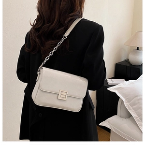 Detail showing creamy white patent leather flap bag with silver S-shaped buckle