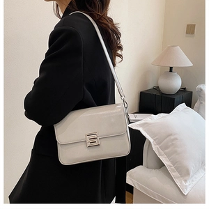 Close-up of the silver geometric lock on a minimalist off-white leather shoulder bag