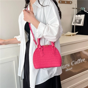 Bolso fucsia con relieve de cocodrilo, forma de concha con asa superior y bandolera