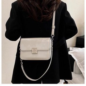 Detailed view of cream leather flap bag with silver geometric buckle on black blazer