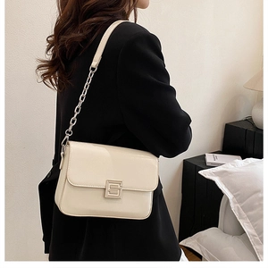Detail of a chic off-white shoulder bag with elegant chain strap and metal buckle