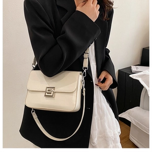 Chic cream white leather shoulder bag with silver metal buckle on a black blazer