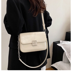 Detail shot of the cream white high-gloss patent leather crossbody bag with a square buckle