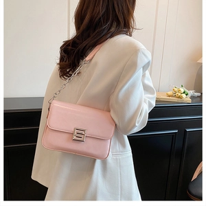 Side view of pink leather shoulder bag with silver S-lock and chain strap on model
