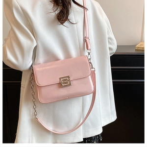 Detail view of pink leather crossbody bag with silver geometric buckle and chain strap