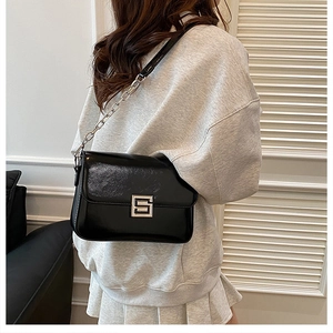 Detail view of the black glossy leather shoulder bag with chic silver chain strap