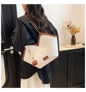 Detailed view of white woven texture tote with brown leather trim and stylish canvas strap