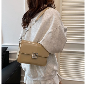 Detail of khaki patent leather bag with silver square metal lock and chain strap