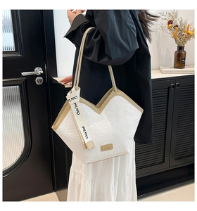 Detail showing white croc-textured tote bag with V-shaped opening and contrast strap