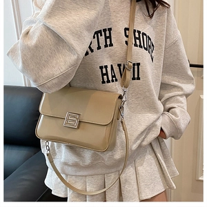Detail shot of a stylish khaki crossbody bag with glossy finish and silver metal buckle