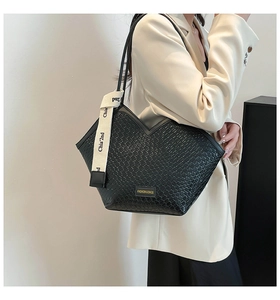 Close-up of a black woven pattern shoulder bag with a fashion logo and letter ribbon strap
