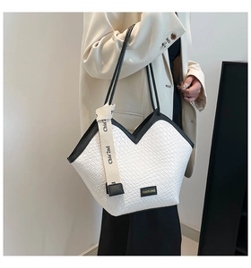Detail of woven texture tote bag with black piping and Chia' 2nd logo strap on model