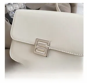 Close-up of cream leather shoulder bag featuring a silver geometric S-shaped buckle