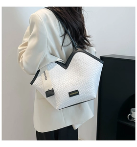 Detail of woven texture tote bag featuring contrast piping and dual detachable straps