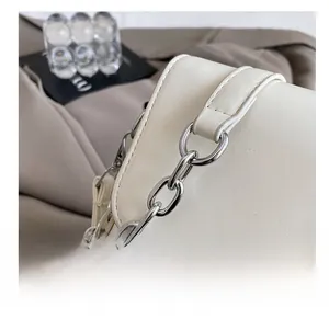 Detail shot of chic off-white leather bag with silver chain and neat stitching