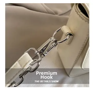 Detail of premium silver-tone metal hook and texture on a beige shoulder bag