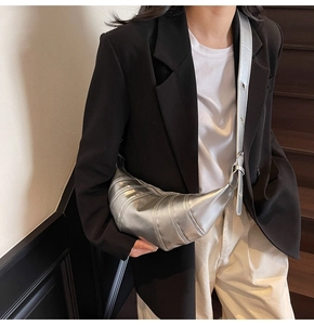 Close-up of metallic silver croissant bag with quilted details on model shoulder