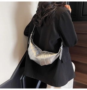 Silver metallic leather croissant bag shown on model in a minimalist interior setting