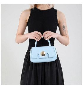 Vue détaillée d'un sac à main bleu clair avec fermoir doré rond et rabat rectangulaire