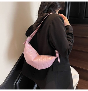 Detailed view of a pink pleated crescent dumpling bag with an adjustable shoulder strap