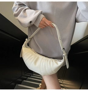 Detail of white pleated dumpling bag with glossy finish and adjustable silver buckle strap