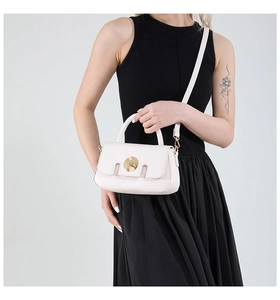 Detailed view of cream leather crossbody bag with gold metal buckle and handle