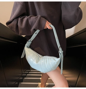 Detail of light blue croissant bag with pleated texture and silver eyelet strap