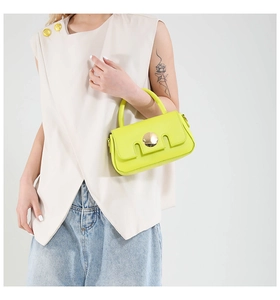 Détail d'un sac à main carré en cuir jaune vif doté d'une grande boucle métallique ronde