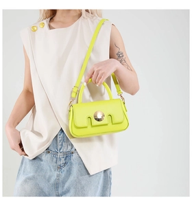 Detail of neon green leather crossbody bag with round gold buckle on a fashion model