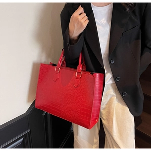 Close-up of red crocodile pattern tote bag with golden metal hardware and double handles