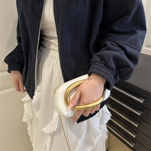 White PU clutch bag with large gold metal ring handle and chain strap on a model