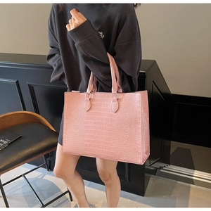 Pink crocodile pattern tote bag shown held by model in a modern indoor lifestyle setting
