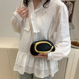 Elegant black oval PU leather handbag with large gold C buckle and chain strap on model