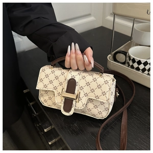 Close-up of beige printed handbag featuring brown floral patterns and gold hardware