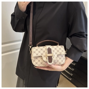 Detail of printed crossbody bag with gold hardware and brown leather shoulder strap