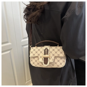 Detail of vintage patterned crossbody bag with gold hardware worn by a model