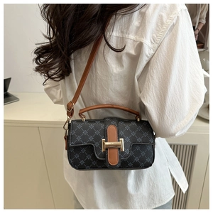 Detail of vintage patterned crossbody bag with brown leather strap and gold metal clasp