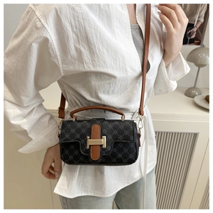 Detail of printed crossbody bag with H-shaped metal buckle and brown leather trim